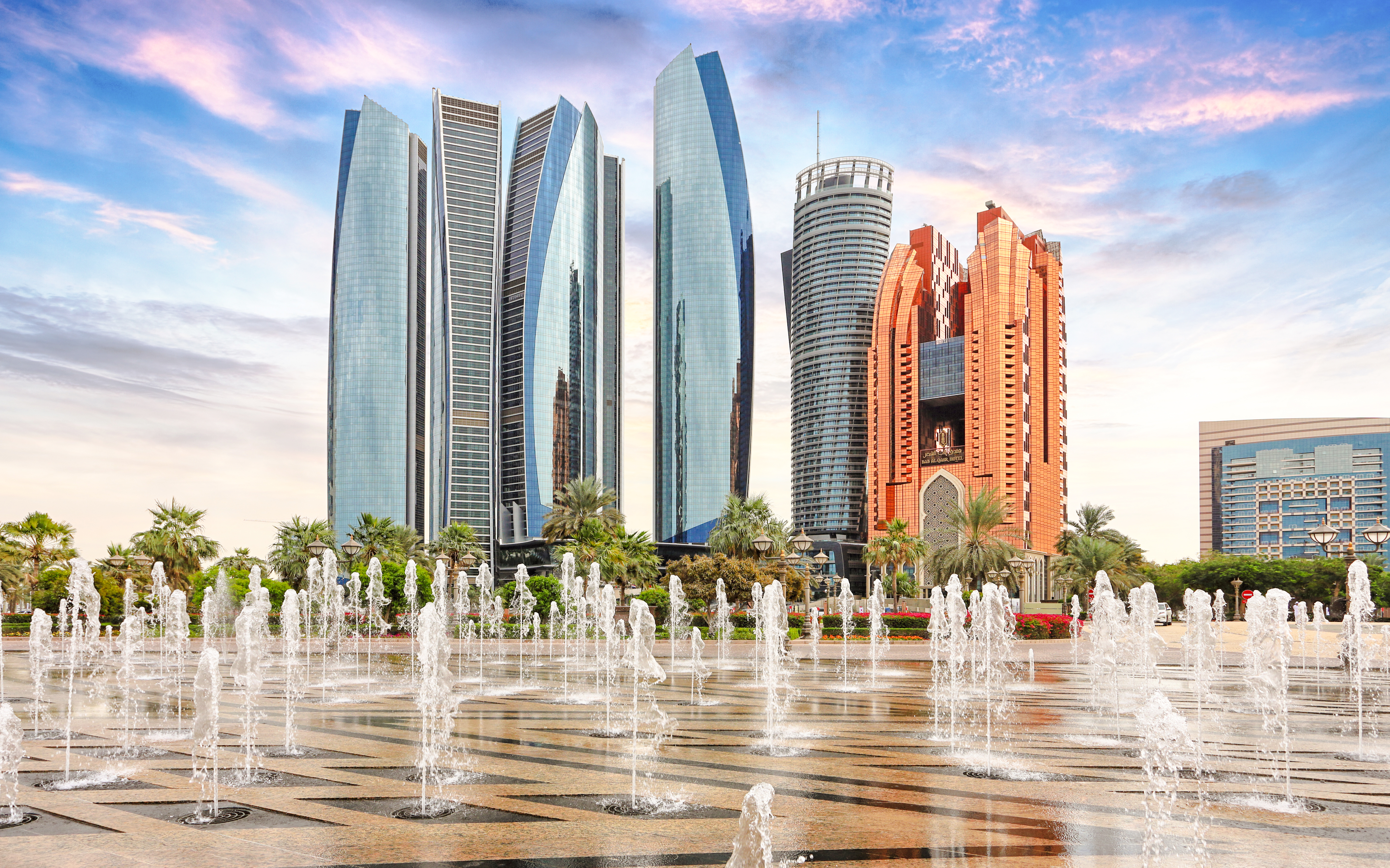 Etihad Towers and fountains in Abu Dhabi at sunset.