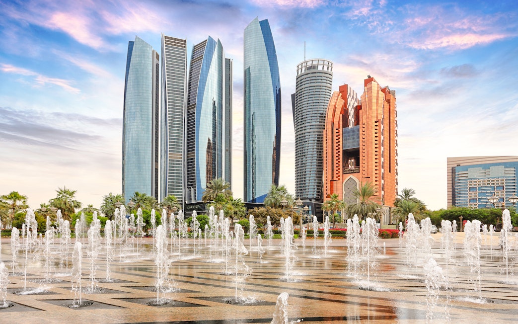 Etihad Towers and fountains in Abu Dhabi at sunset.
