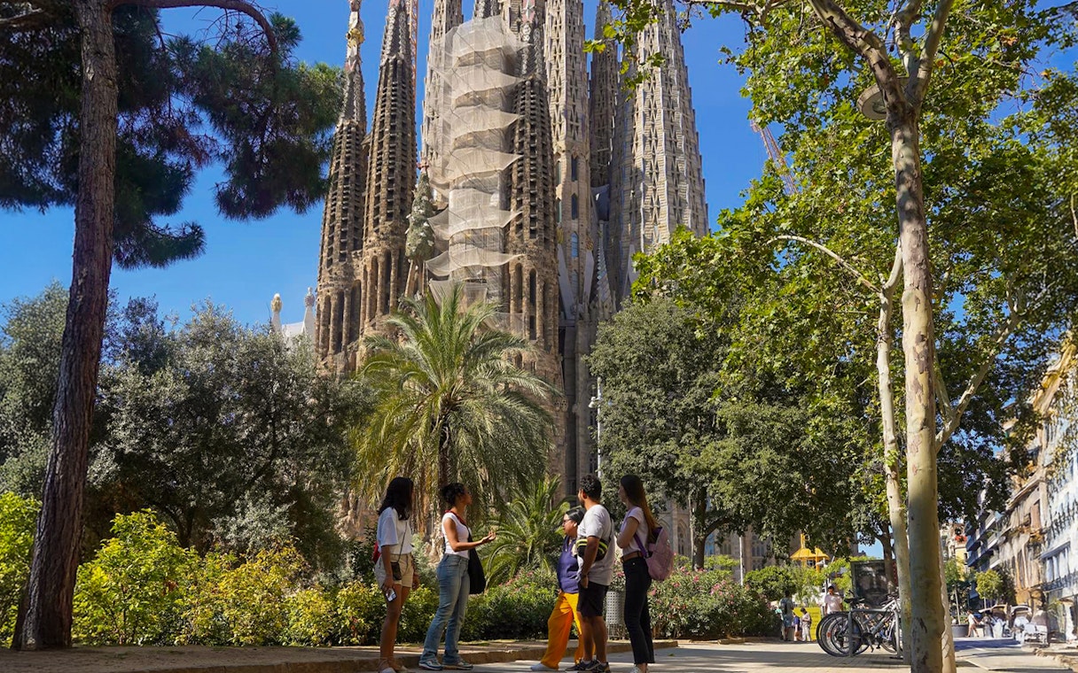 Tour group near Sagrada Familia in Barcelona, surrounded by trees.