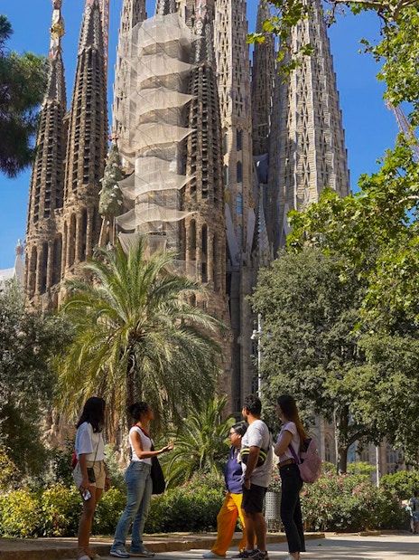 Tour group near Sagrada Familia in Barcelona, surrounded by trees.