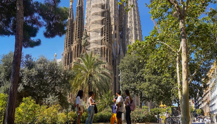 Tour group near Sagrada Familia in Barcelona, surrounded by trees.
