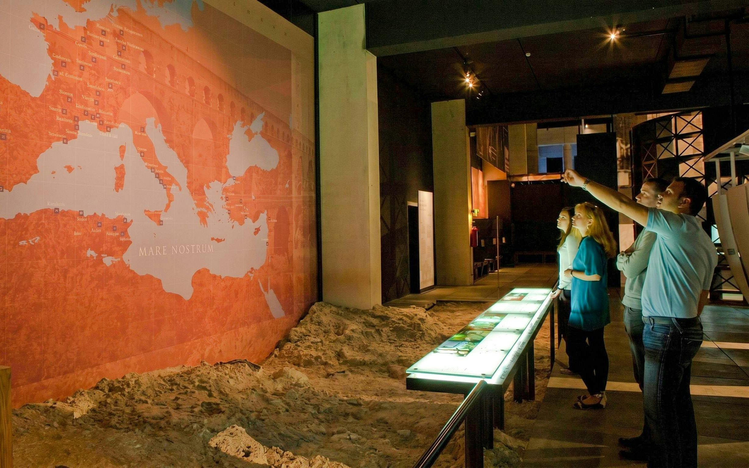 Visitors observing a historical map exhibit at Pont du Gard Museum.