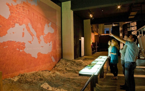 Visitors observing a historical map exhibit at Pont du Gard Museum.