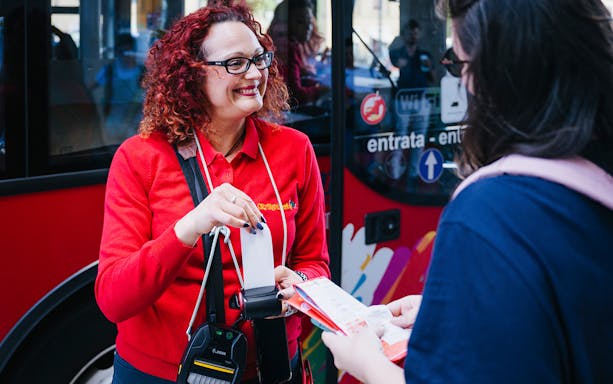 Bus staff assisting customer with ticketing.