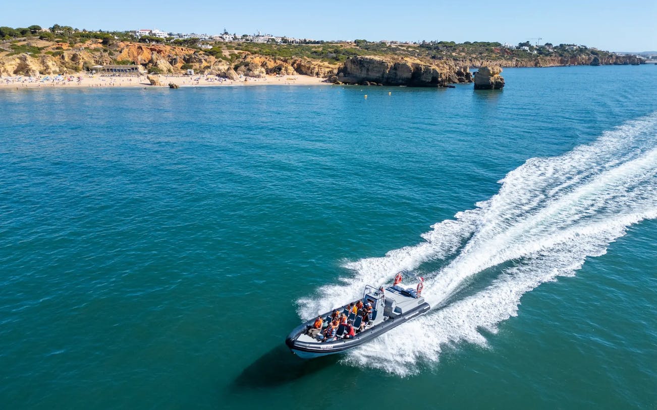 Tourists on RIB boat approaching Benagil Caves, Portugal coastline.