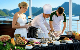 Chef leading cooking class on Lan Ha Bay 5-Star Premium Cruise with guests preparing dishes.