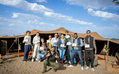 Group holding certificates in front of a Berber tent after a hot air balloon flight in Marrakech.