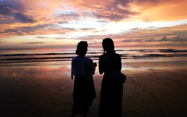 Silhouettes on a beach at sunset during Kawa Kawa Fireflies & Sunset Cruise Night Tour.