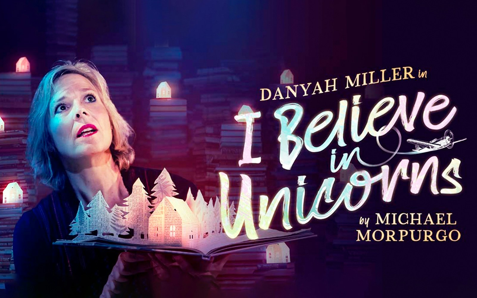 Person holding an open book with paper cut-out trees and houses, "I Believe In Unicorns" text.