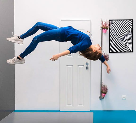 Person appearing to float sideways in a room at the Museum of Illusions.