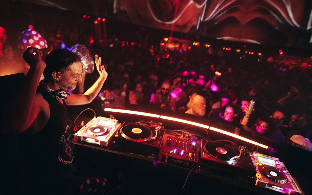 DJ performing at Club Chinois with vibrant crowd and colorful lights.