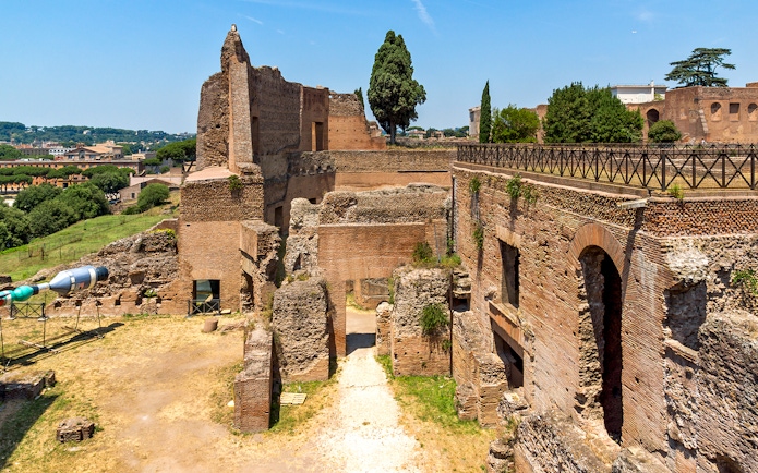 Roman Forum ruins with ancient brick structures and Palatine Hill in Rome.