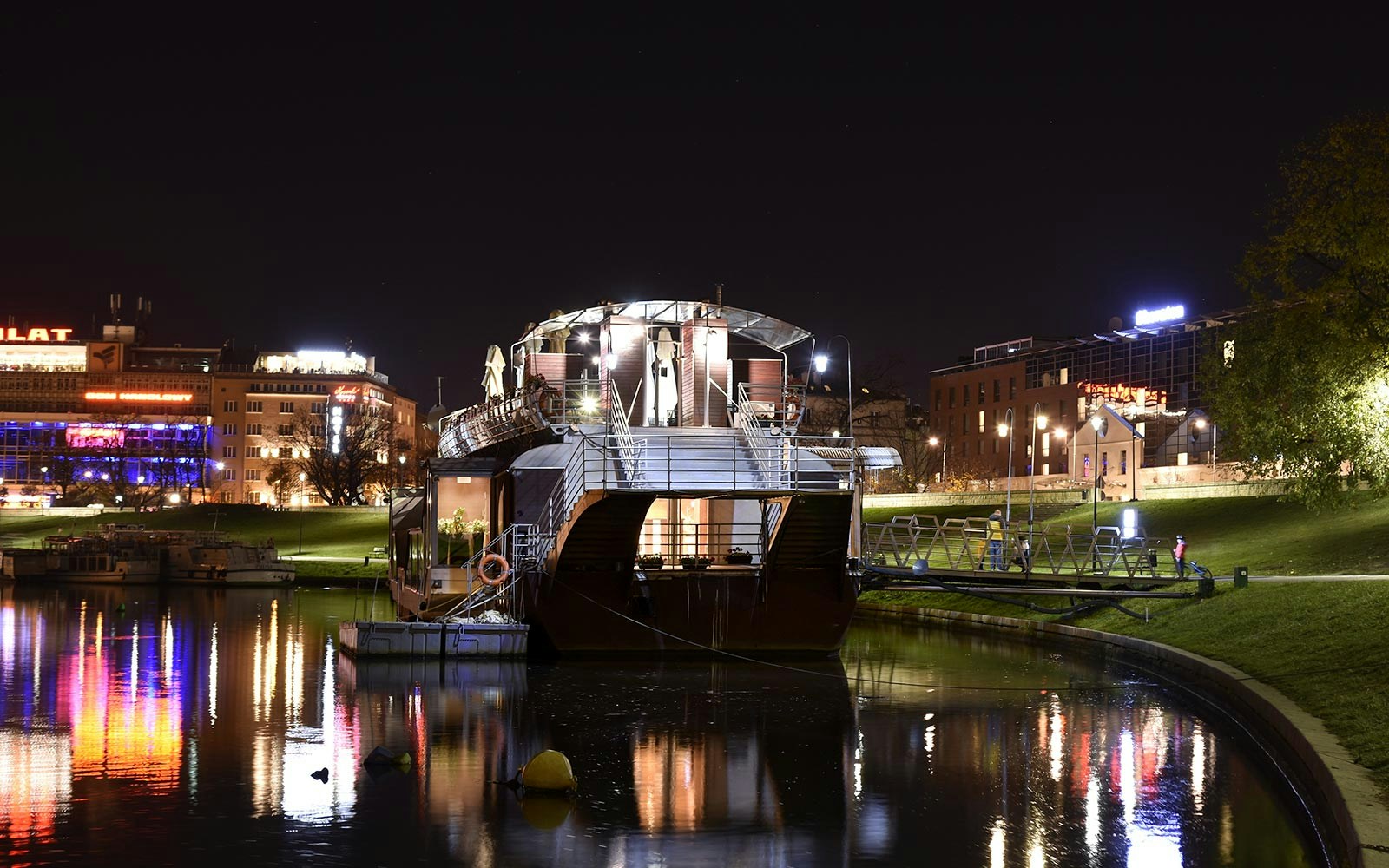 Vistula River night cruise with illuminated Krakow skyline in the background.