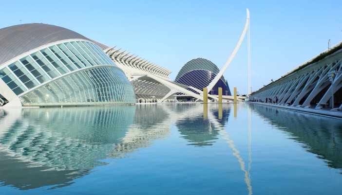 Hemisferic building in Valencia, Spain, reflecting in water at sunset.