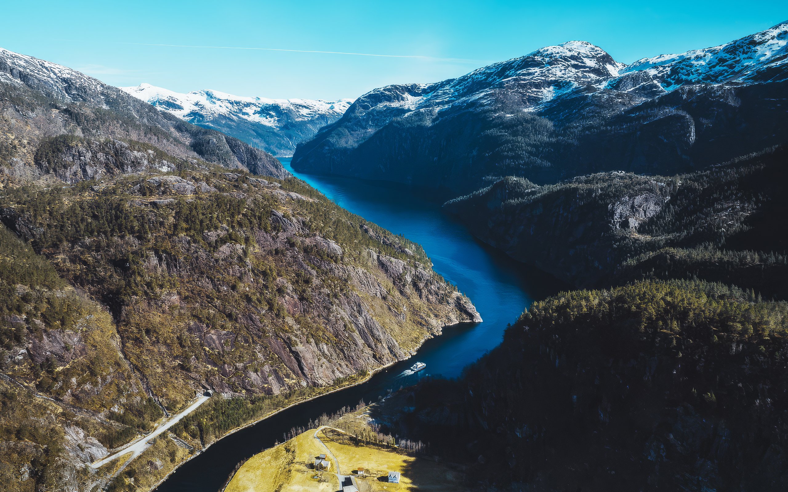 Aerial view of a deep fjord winding between steep, forested mountains.