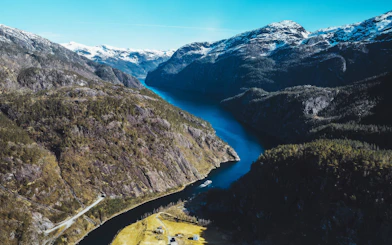 Aerial view of a deep fjord winding between steep, forested mountains.