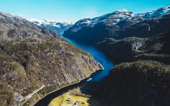 Aerial view of a deep fjord winding between steep, forested mountains.