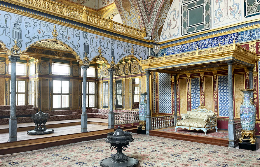 Interior of Topkapi Palace Museum with ornate gold and blue decorations and a lavish seating area.