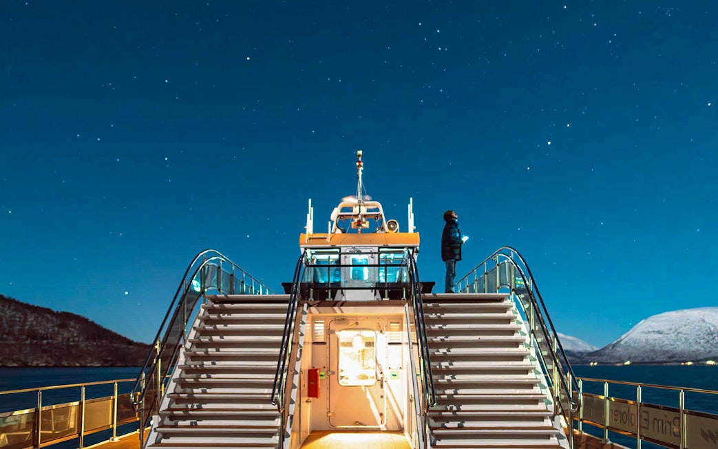 Cruise ship deck under starry sky during Northern Lights tour.