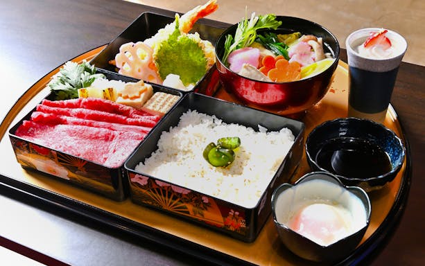 Traditional Japanese bento with rice, vegetables, and a bowl of chicken hot pot.