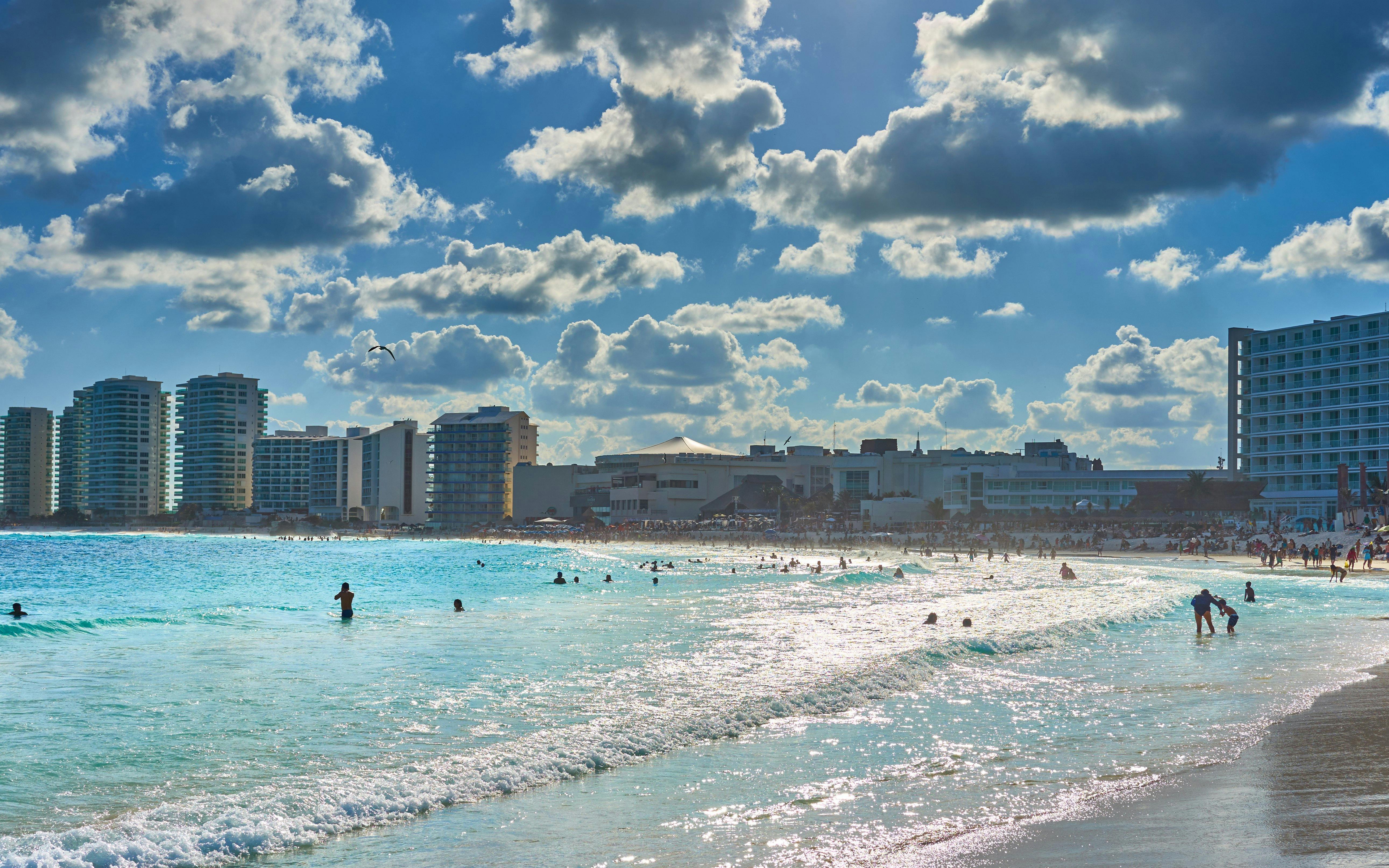 Beachfront view of Mandala Beachclub Cancun with people enjoying the ocean.