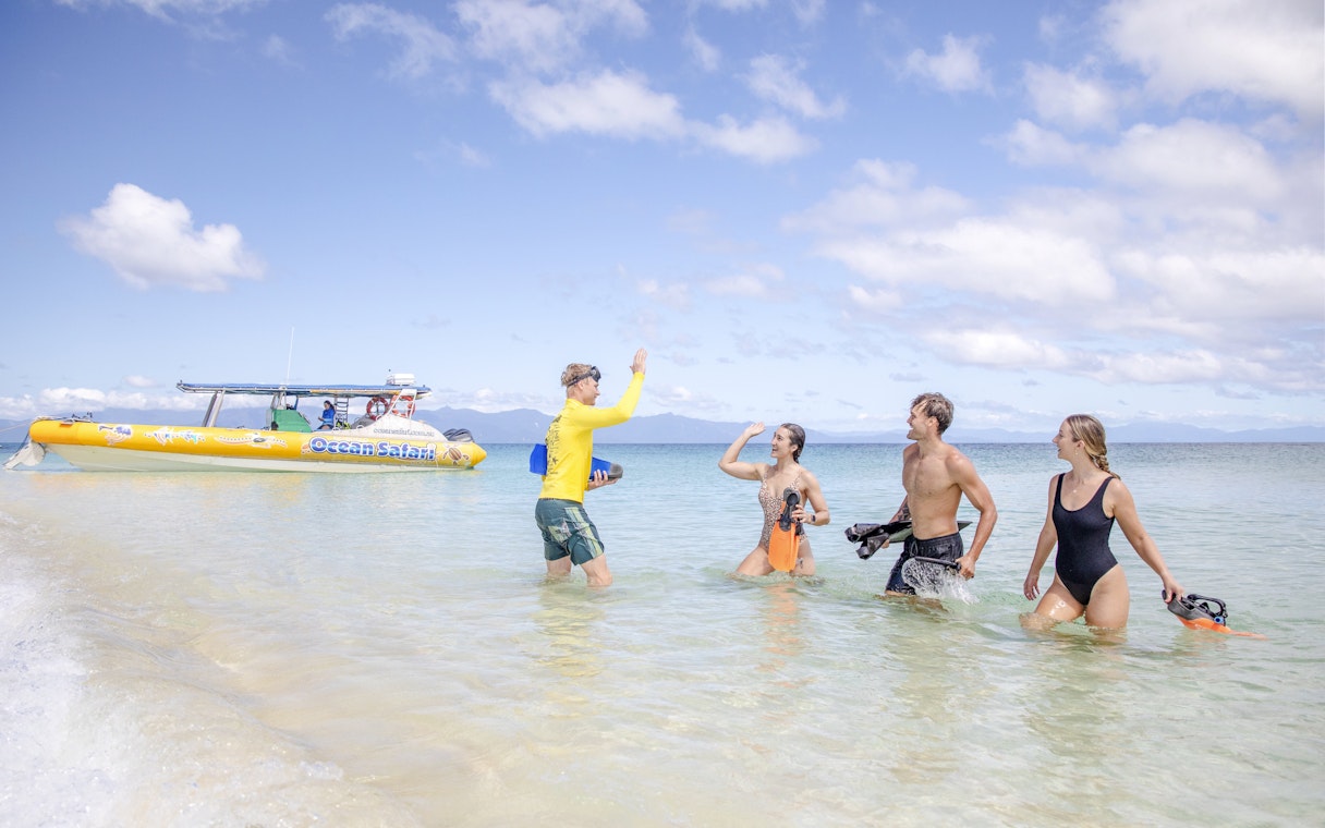Snorkelers high-five near a boat on a Great Barrier Reef guided tour.