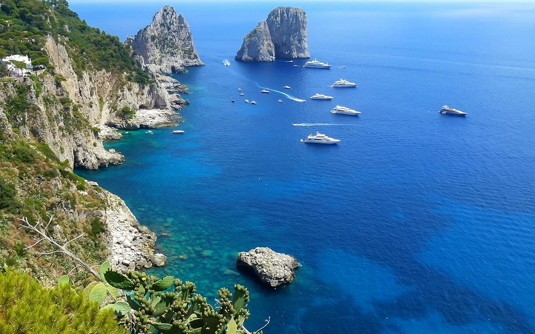 Boats near rocky cliffs on the Amalfi Coast during a small-group tour from Naples.