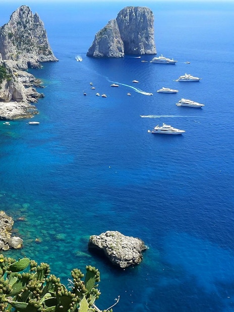 Boats near rocky cliffs on the Amalfi Coast during a small-group tour from Naples.
