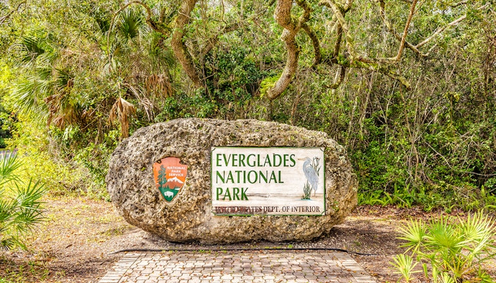 Everglades National Park entrance sign surrounded by lush greenery.