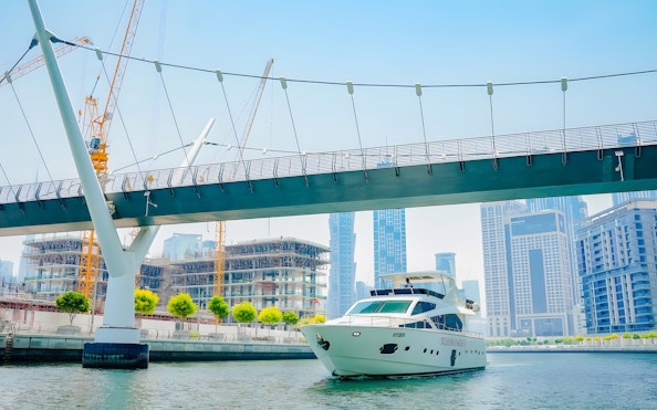 Yacht cruising through Dubai canal with Burj Khalifa and skyline in the background.