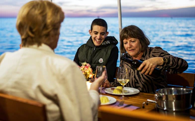 Guests enjoying drinks and dessert on a boat at sunset.