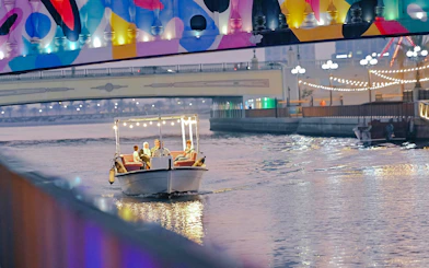 Boat tour under colorful bridge lights in Sharjah.
