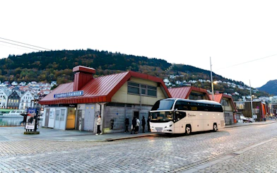 Bus station in Strandkaien with parked tour bus and surrounding hillside houses.