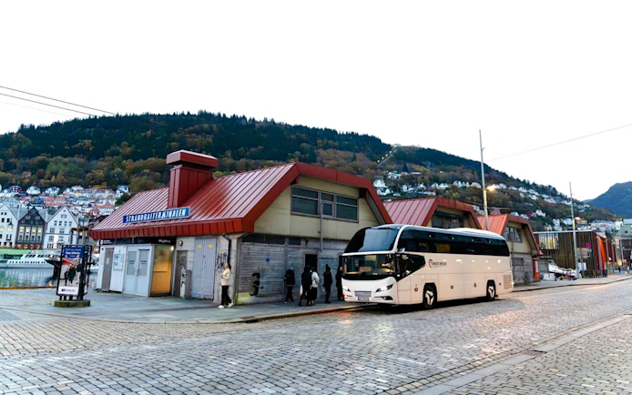 Bus station in Strandkaien with parked tour bus and surrounding hillside houses.