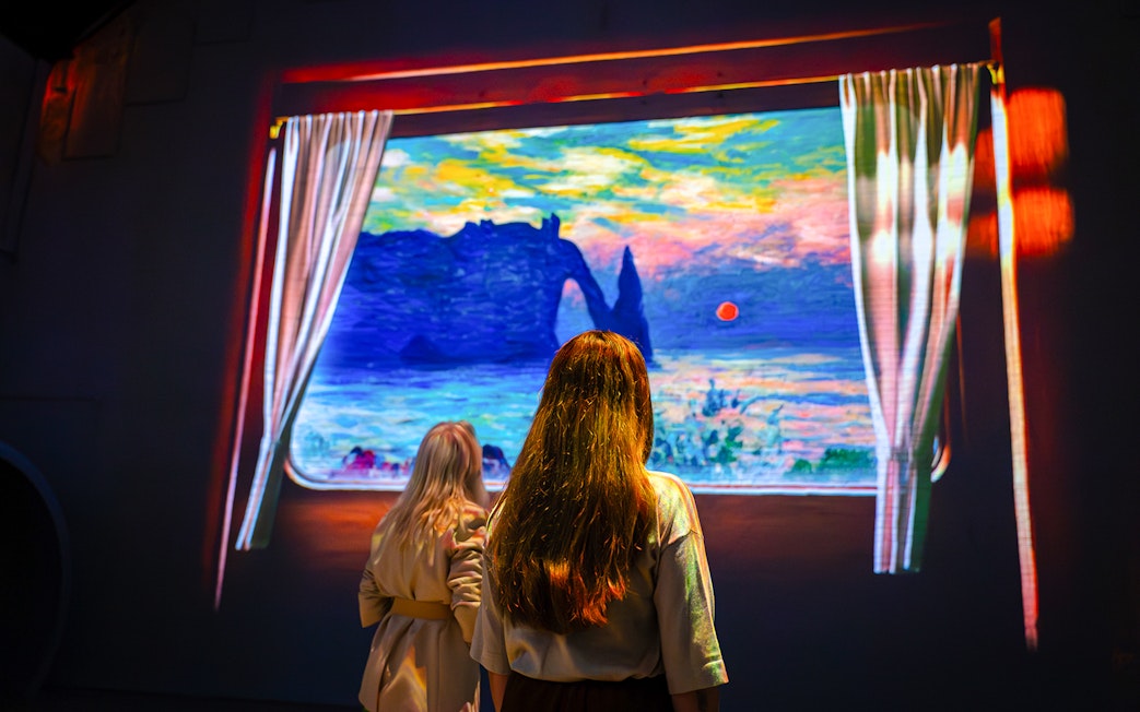 Visitors viewing Monet's artwork at Fabrique des Lumières exhibition.