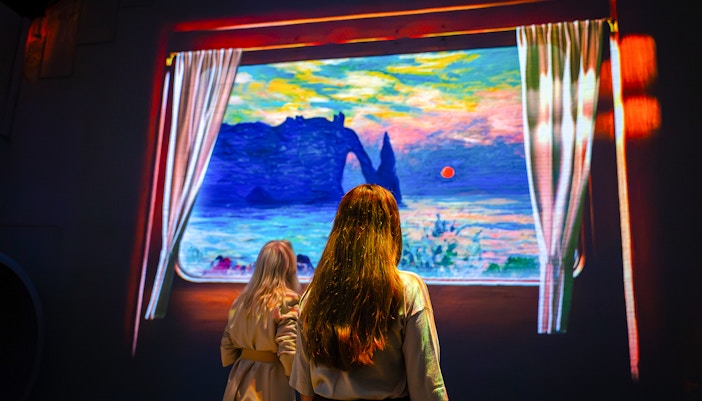 Visitors viewing Monet's artwork at Fabrique des Lumières exhibition.