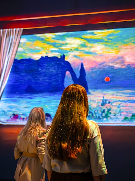 Visitors viewing Monet's artwork at Fabrique des Lumières exhibition.