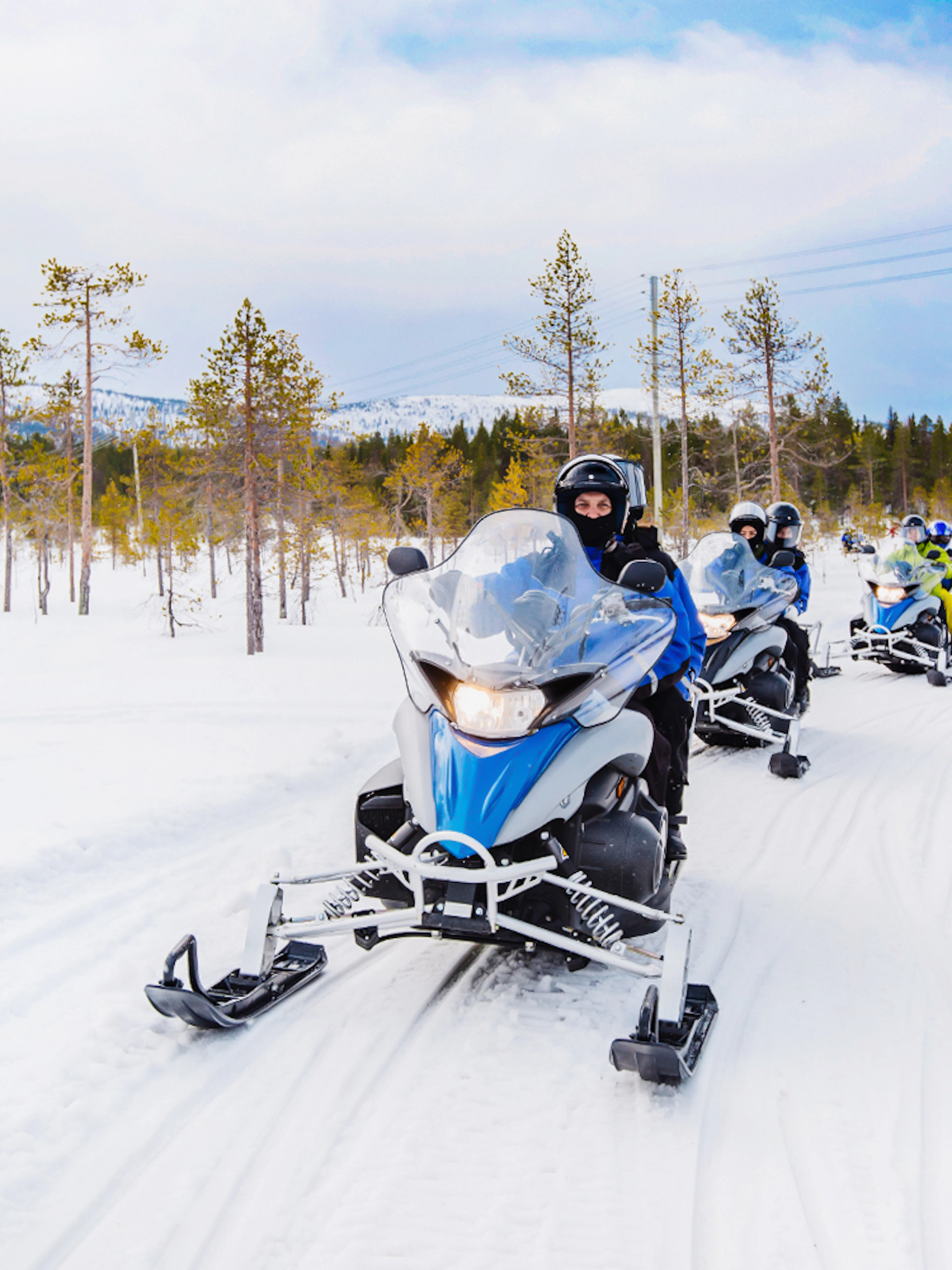 Snowmobilers riding through snowy forest near Zakopane, Poland.