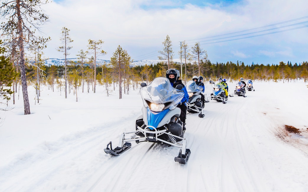 Snowmobilers riding through snowy forest near Zakopane, Poland.