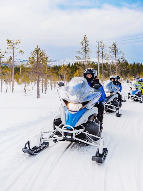 Snowmobilers riding through snowy forest near Zakopane, Poland.