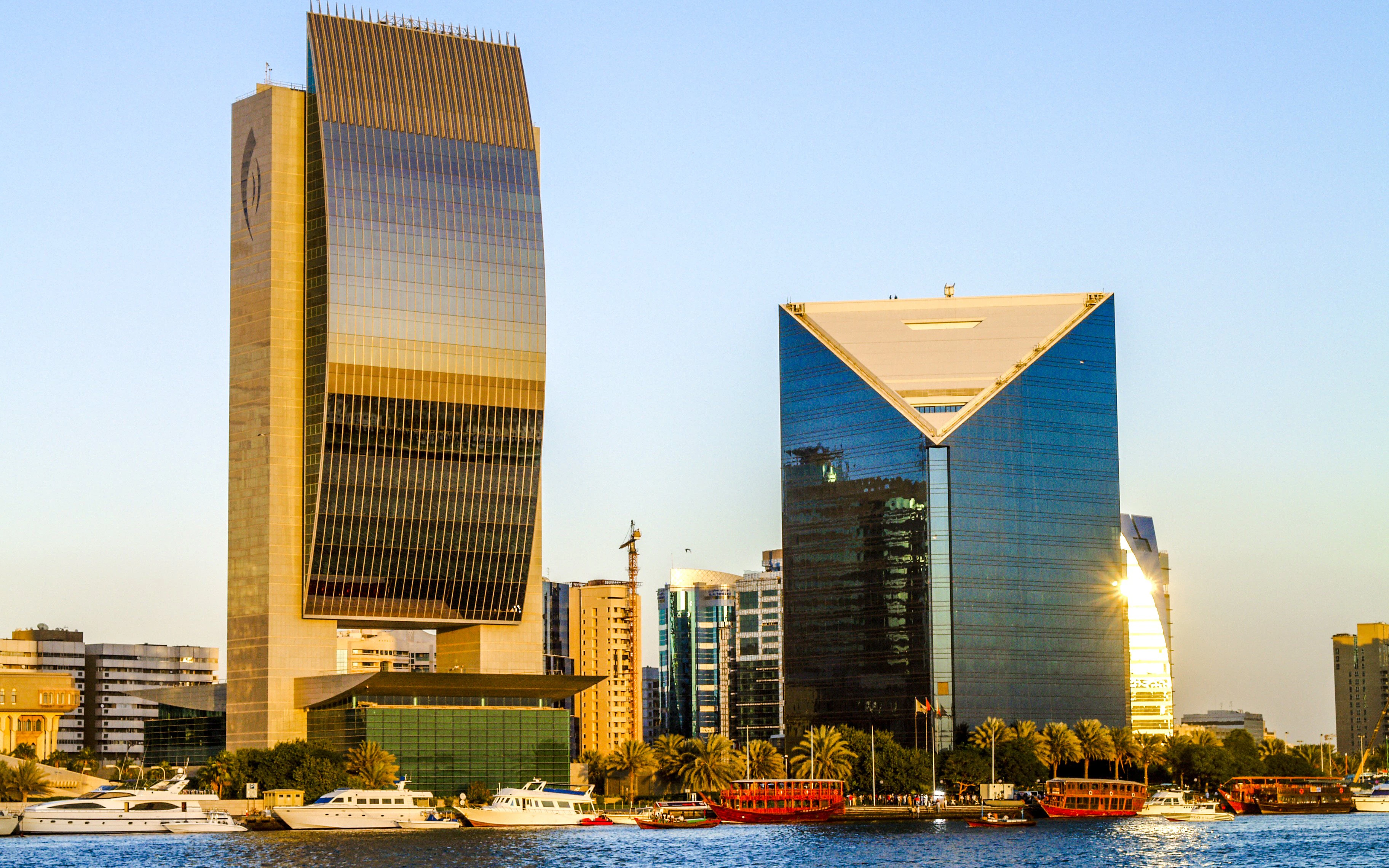 Dubai Creek with modern skyscrapers and boats near the national bank.