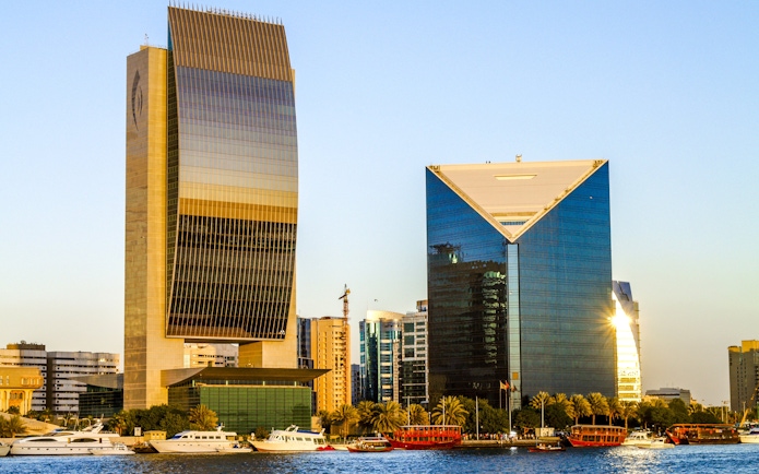Dubai Creek with modern skyscrapers and boats near the national bank.