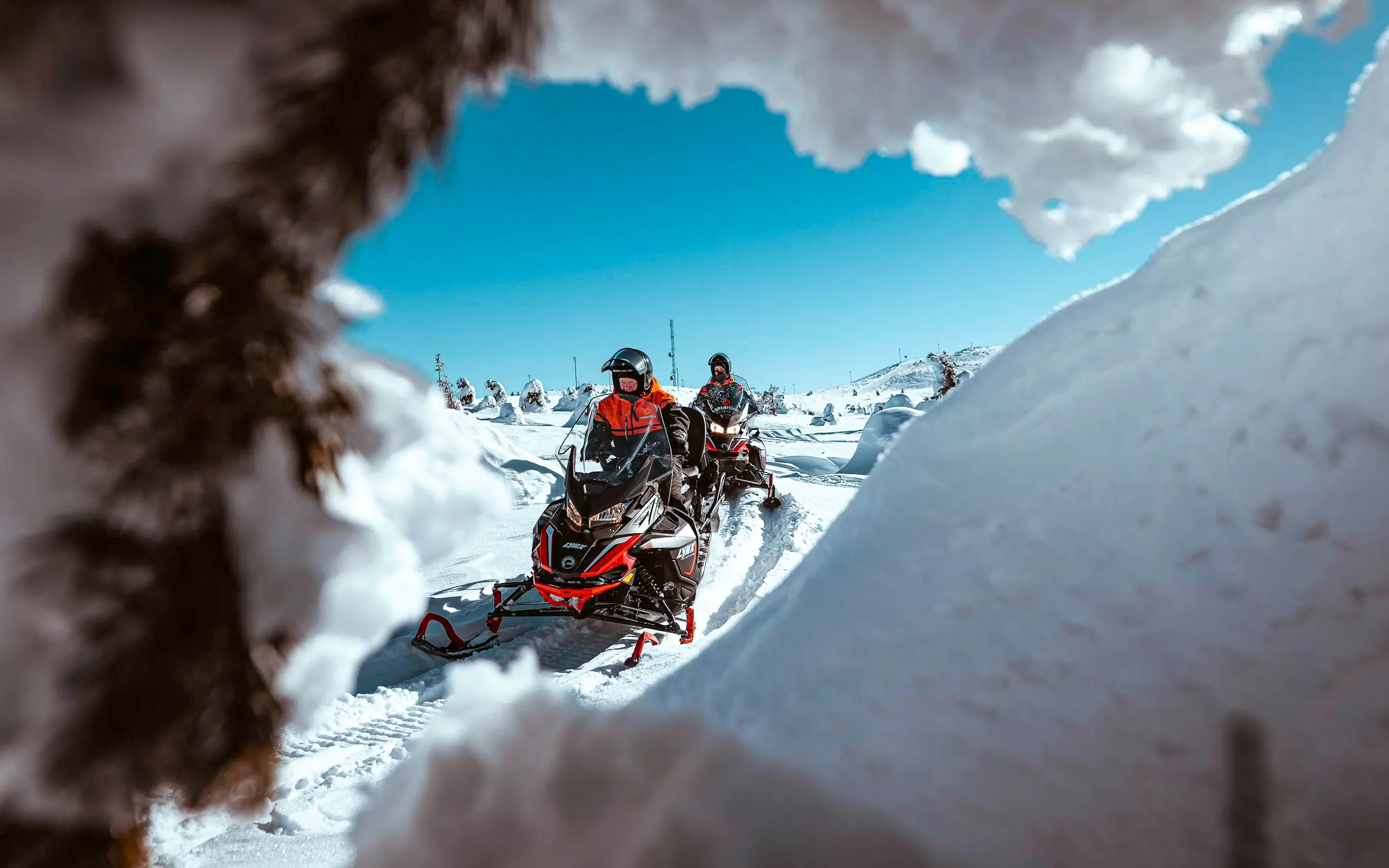 Snowmobilers riding through snowy landscape in Rovaniemi.