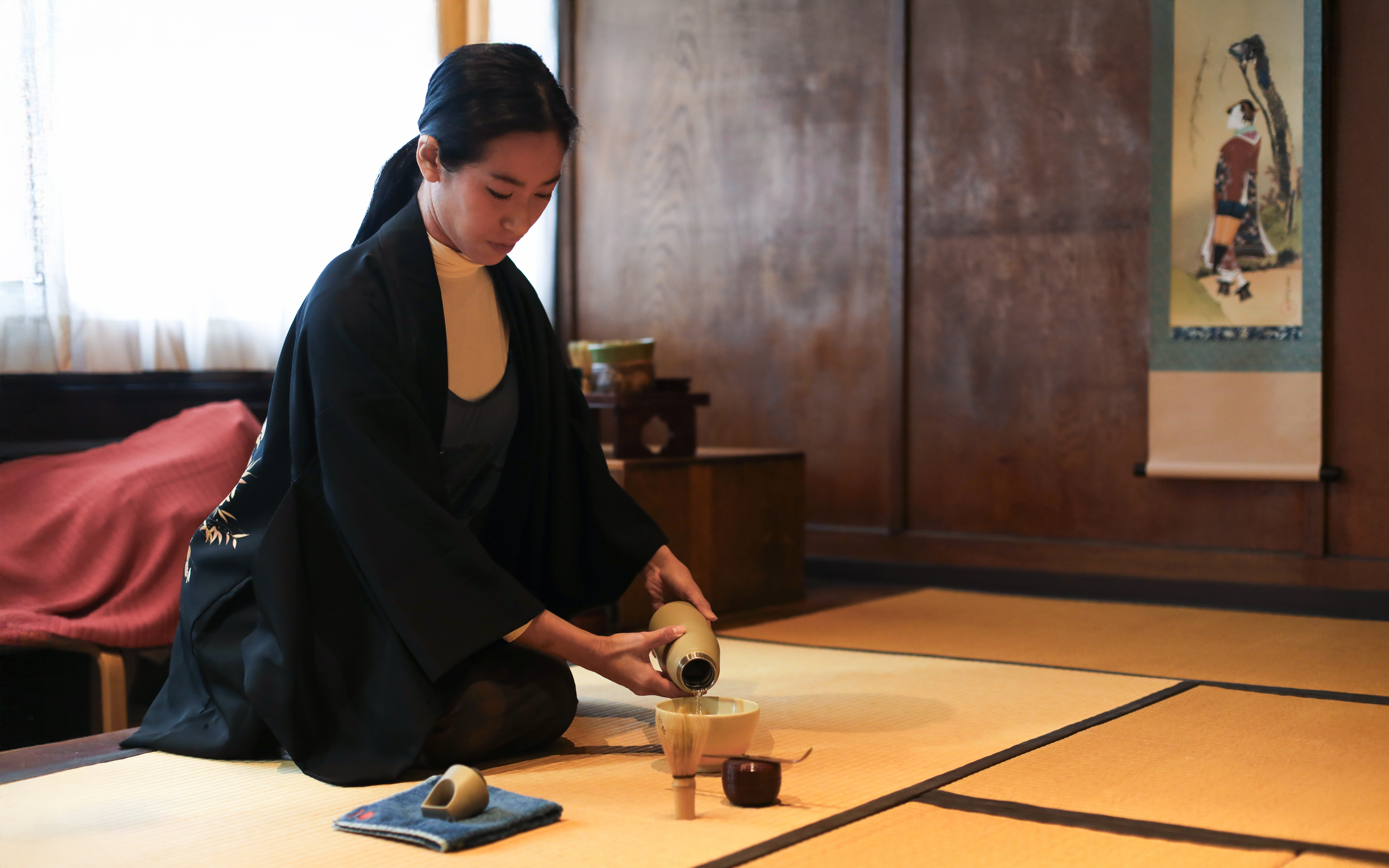 Guide performing traditional tea ceremony in Japanese room.