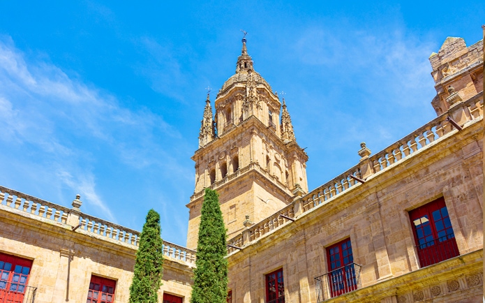 Bell tower of Salamanca Cathedral against blue sky.