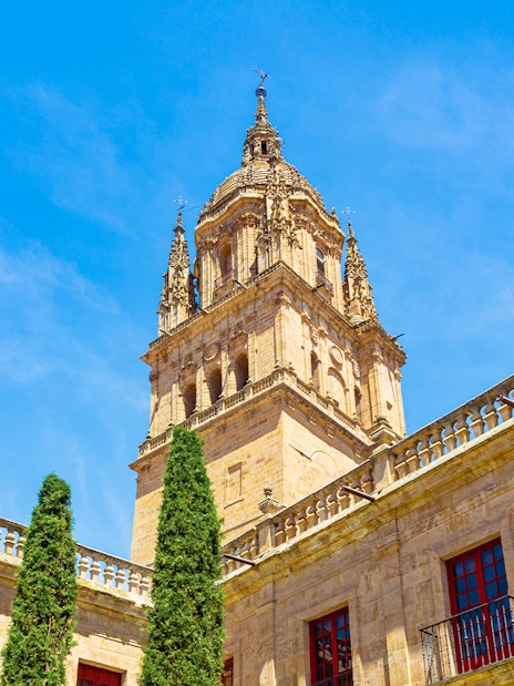 Bell tower of Salamanca Cathedral against blue sky.