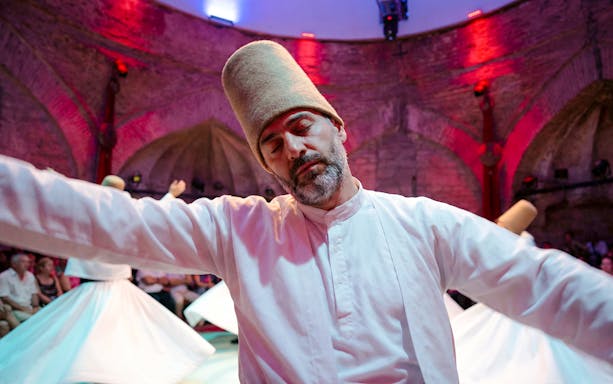 Whirling Dervish performing in traditional attire during a show.