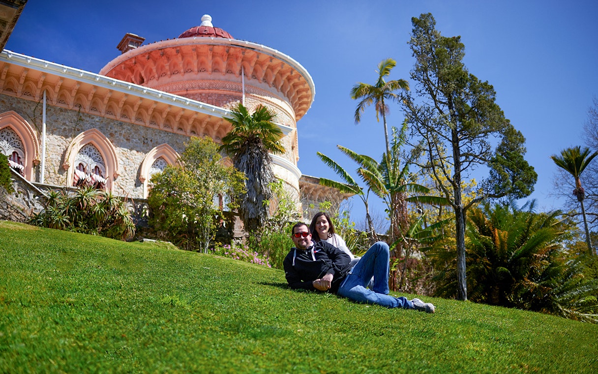 Couple relaxing on grass in front of Monserrate Palace, Sintra, Portugal.