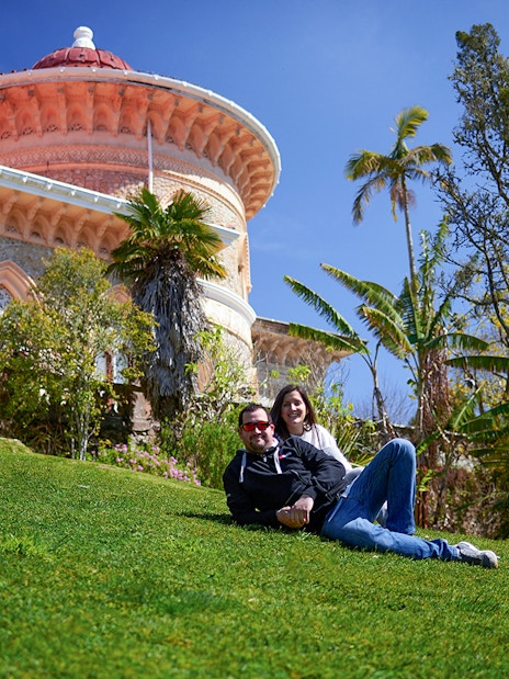 Couple relaxing on grass in front of Monserrate Palace, Sintra, Portugal.