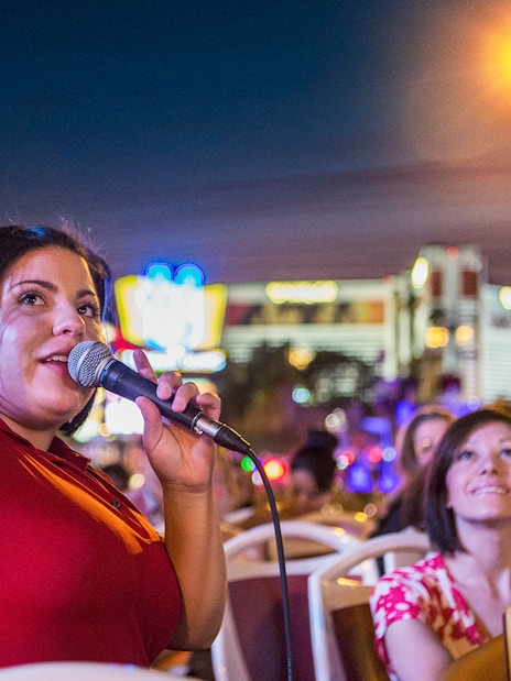 Tour guide speaking on a microphone during a panoramic night tour in a city.